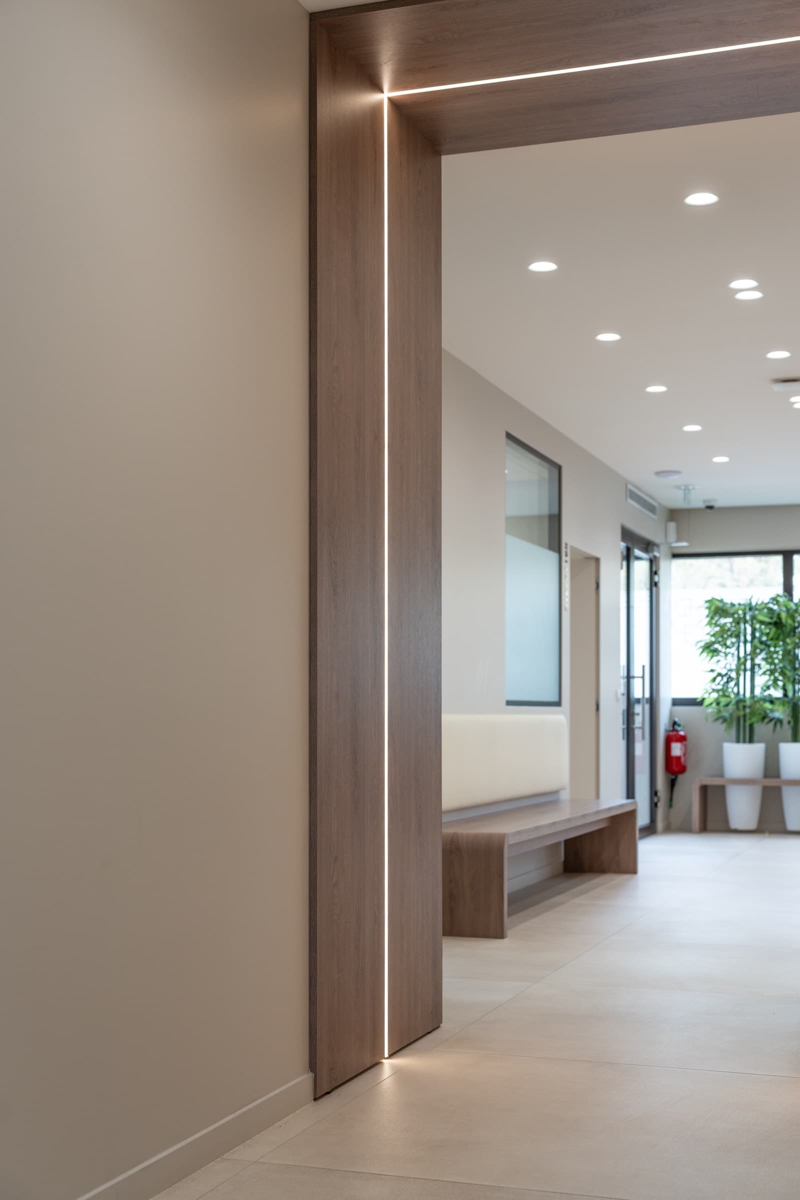 Couloir architectural avec encadrement en bois et bande LED, espace d'attente en arrière-plan
