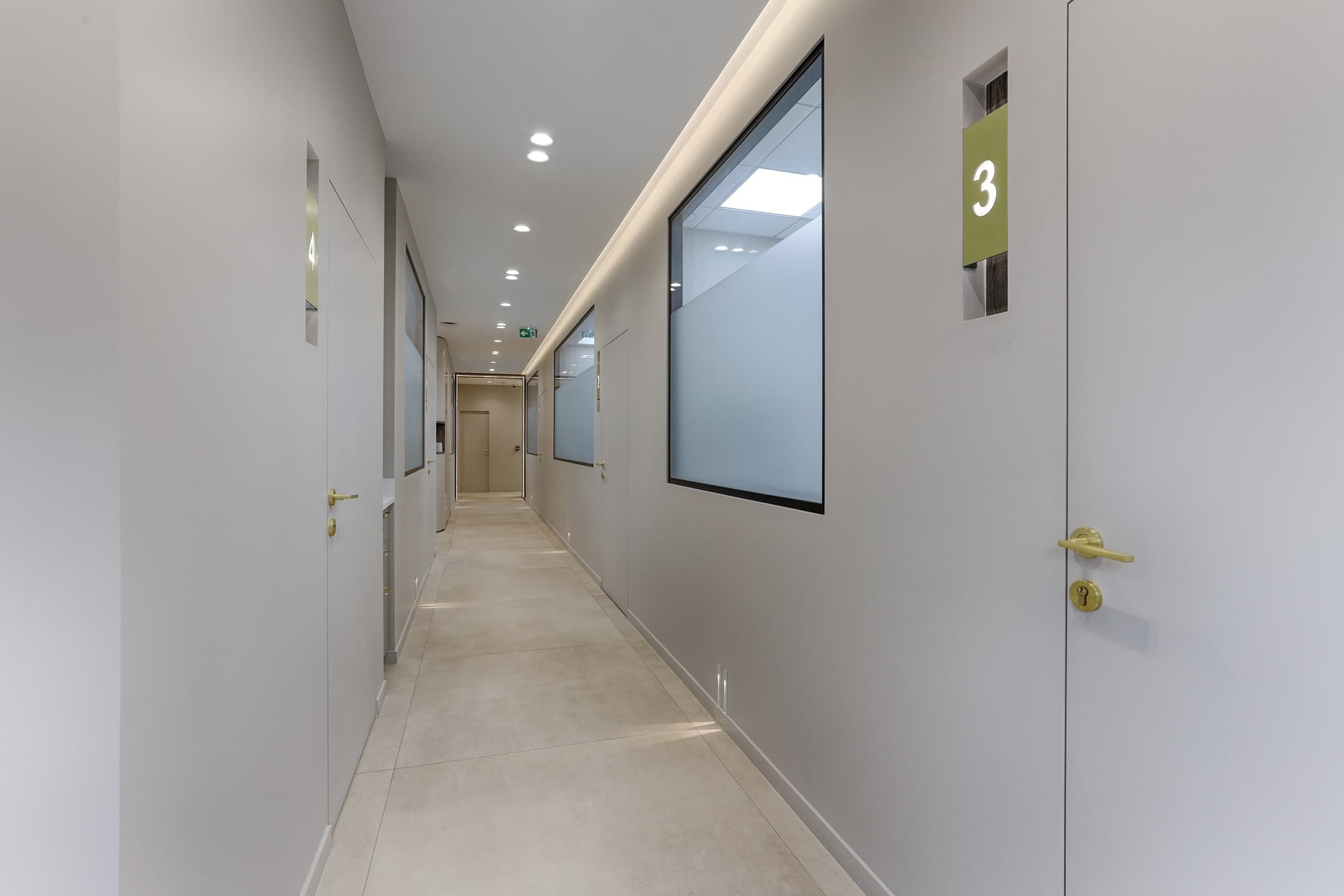 Couloir avec portes de salles de soin numérotées en laiton