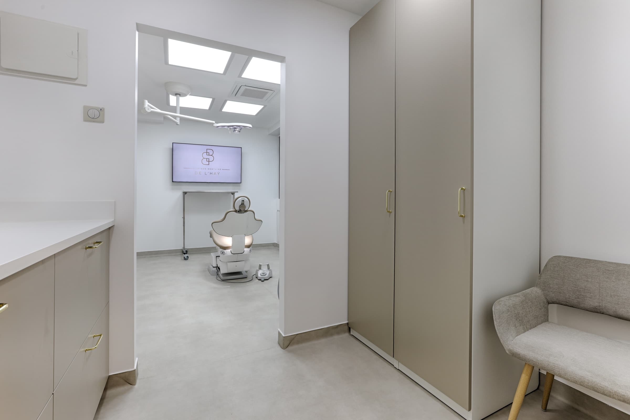 Couloir vers une salle de soin avec fauteuil dentaire visible et écran logo