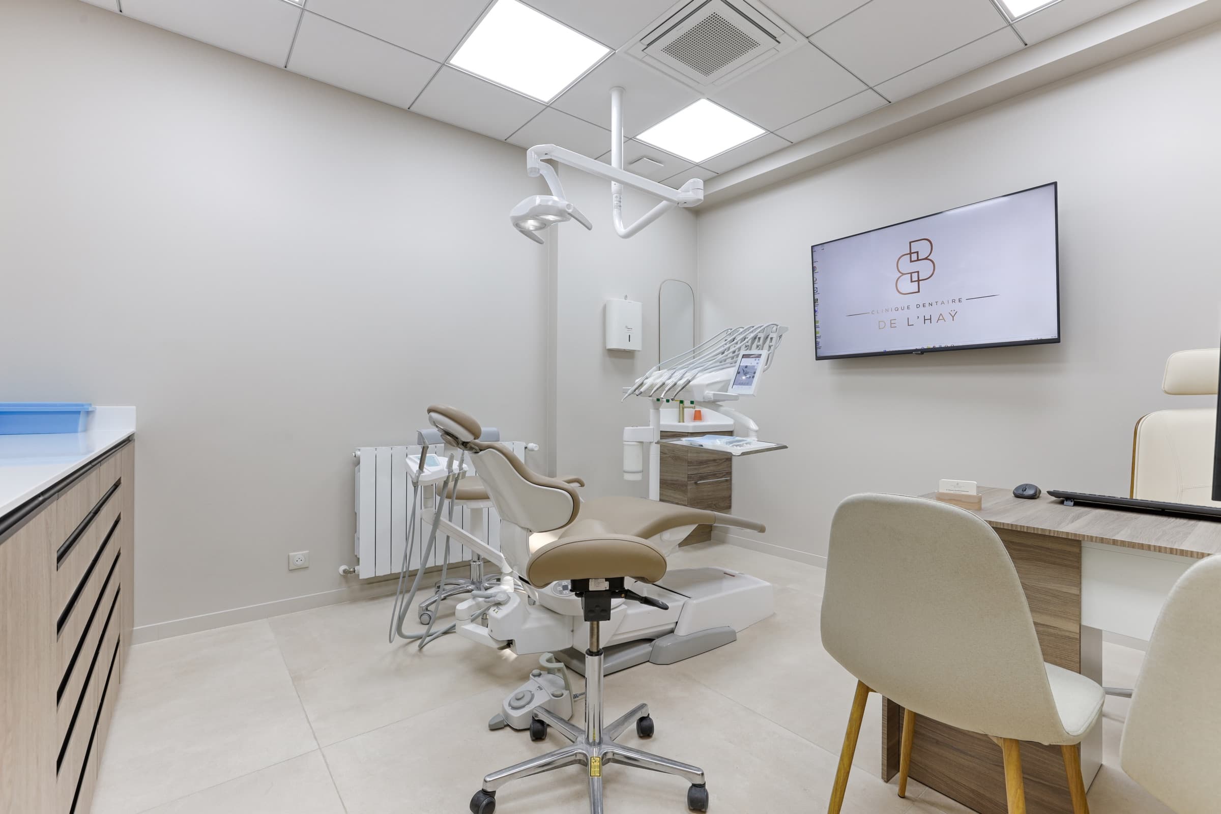 Salle de soin avec fauteuil dentaire beige et écran logo BB doré